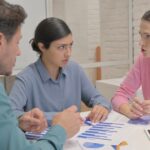 Team reviewing documents and making decisions under pressure during a meeting, with hands pointing and discussing options